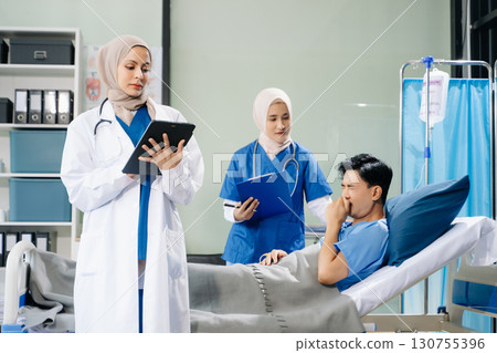 Doctors and nurses in hijabs offering care to a patient in a hospital ward, showcasing teamwork, professionalism 130755396