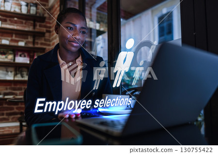 Professional reviewing employee selections while working on a laptop in a modern workspace during evening hours Professional reviewing employee selections while working on a laptop in a modern workspace during evening hours 130755422