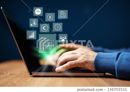 Hands typing on laptop with digital financial icons and data analytics displayed on screen in a modern workspace 130755531