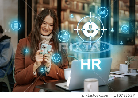 Young woman uses smartphone for job search while sitting at a cafe in the evening Young woman uses smartphone for job search while sitting at a cafe in the evening 130755537