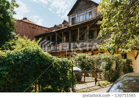 Historic wooden house in a green neighborhood on a sunny day with blue sky and lush vegetation 130755565