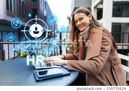 Professional woman working on laptop outdoors with HR icons displayed, showcasing modern recruitment technology Professional woman working on laptop outdoors with HR icons displayed, showcasing modern recruitment technology 130755624