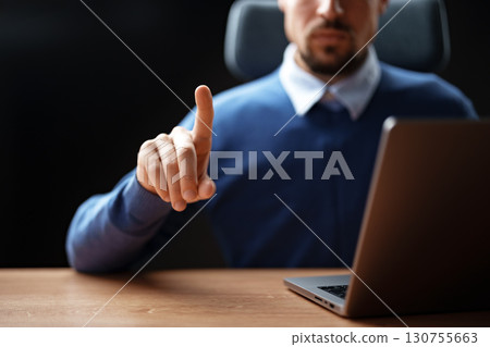 Person gestures with a finger raised while sitting at a desk with a laptop during a business meeting setting Person gestures with a finger raised while sitting at a desk with a laptop during a business meeting setting 130755663