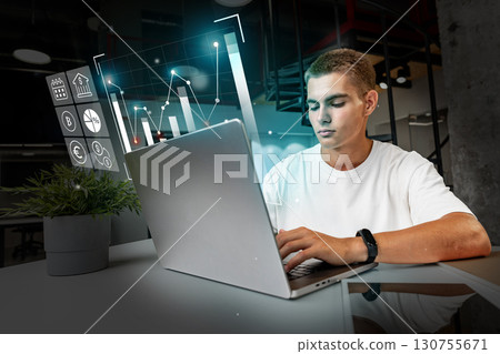 Young adult analyzing data on a laptop in a modern workspace during daytime near urban center Young adult analyzing data on a laptop in a modern workspace during daytime near urban center 130755671