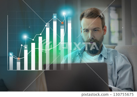 Young man analyzes financial trends and market growth while working on laptop in a modern living space Young man analyzes financial trends and market growth while working on laptop in a modern living space 130755675