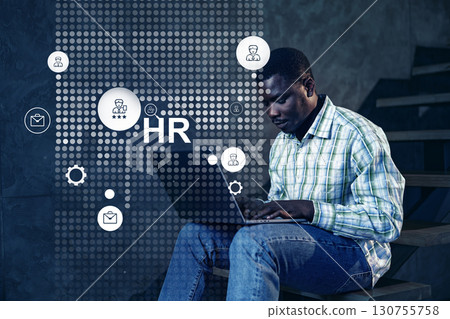 Professional engaged in human resources tasks while using a laptop in a modern office setting 130755758