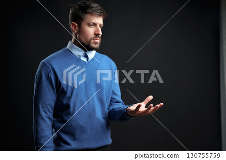 Male in blue sweater contemplates with thoughtful expression in studio setting during indoor shoot 130755759