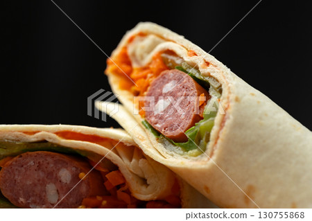Delicious wrap filled with sausage, fresh vegetables, and vibrant carrots prepared for a satisfying meal 130755868