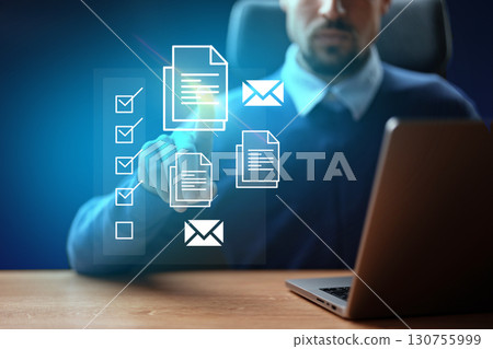 Working professional using laptop to manage documents and emails in a modern office environment during nighttime 130755999