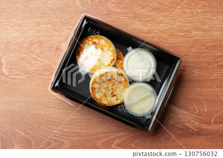 Delicious warm pancakes served with sweet syrup and creamy topping on a wooden table 130756032