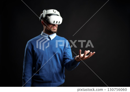 Man wearing virtual reality headset engages with digital environment in indoor studio setting Man wearing virtual reality headset engages with digital environment in indoor studio setting 130756060
