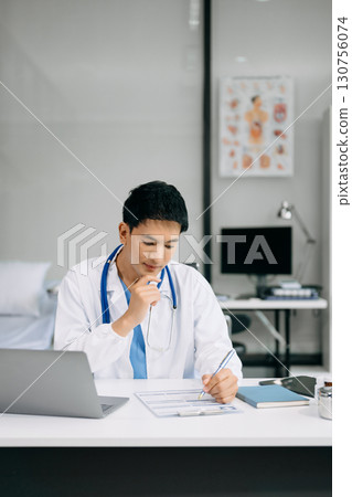 Doctor sit on table in office hospital. Attractive therapist female practitioner pharmacist smile and use tablet and laptop. after success work from treatment Doctor sit on table in office hospital. Attractive therapist female practitioner pharmacist smile and use tablet and laptop. after success work from treatment 130756074