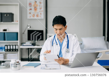 Doctor sit on table in office hospital. Attractive therapist female practitioner pharmacist smile and use tablet and laptop. after success work from treatment Doctor sit on table in office hospital. Attractive therapist female practitioner pharmacist smile and use tablet and laptop. after success work from treatment 130756076