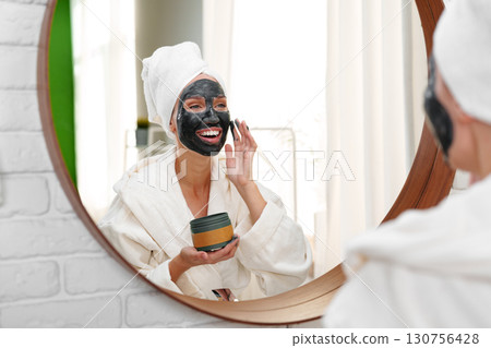 Woman applying facial mask in cozy bathroom during self-care routine in the morning Woman applying facial mask in cozy bathroom during self-care routine in the morning 130756428