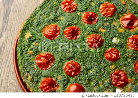 Savory spinach tart with roasted tomatoes on wooden table under warm light Savory spinach tart with roasted tomatoes on wooden table under warm light 130756455