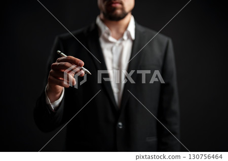 Business professional gestures with pen in hand during presentation in studio setting 130756464