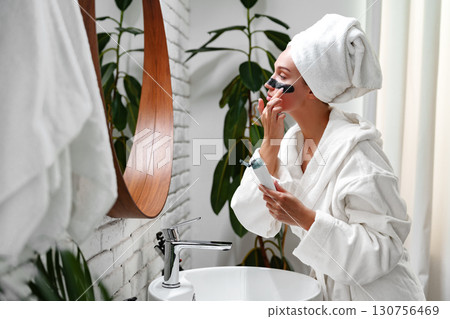 Woman preparing for her day in a modern bathroom with elegant decor and natural elements 130756469