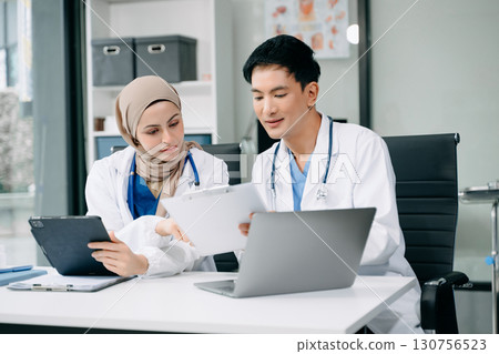 Doctors analyzing results or diagnosis of patient in clinic. Teamwork, medical and healthcare workers in discussion and research on tablet device 130756523