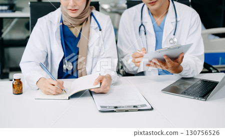 Doctors analyzing results or diagnosis of patient in clinic. Teamwork, medical and healthcare workers in discussion and research on tablet device 130756526