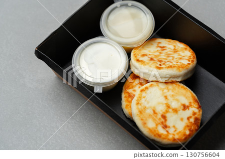 Delicious breakfast with fluffy pancakes and creamy sauces served in a takeout container 130756604