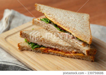 Delicious sandwich with fresh ingredients served on wooden board in cozy setting at lunchtime 130756686