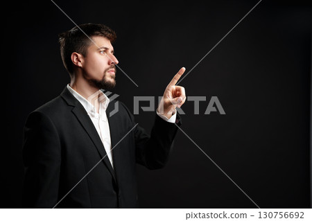 Business professional directing attention in an engaged discussion against a dark backdrop 130756692