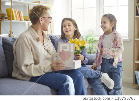 Happy Mothers Day for senior granny, loving small grandchildren greeting excited mature lady Happy Mothers Day for senior granny, loving small grandchildren greeting excited mature lady 130756763