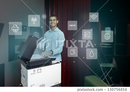 Young man using a multifunction printer in an office environment, showcasing modern technology and digital integration 130756858