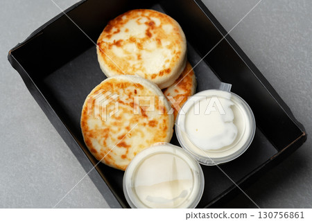 Freshly prepared biscuits paired with creamy toppings served in a black takeout container 130756861