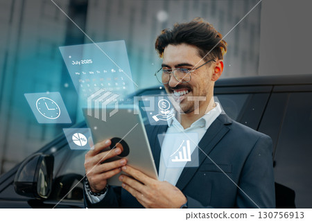 Business professional uses tablet in front of modern vehicle while analyzing data and planning for future success 130756913