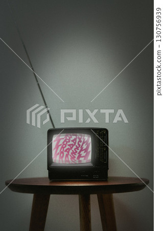 Vintage television set displaying static with colorful text on screen in dimly lit room 130756939