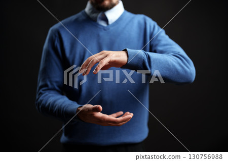 Man performing a hand gesture in a studio setting with dramatic lighting during a creative session 130756988