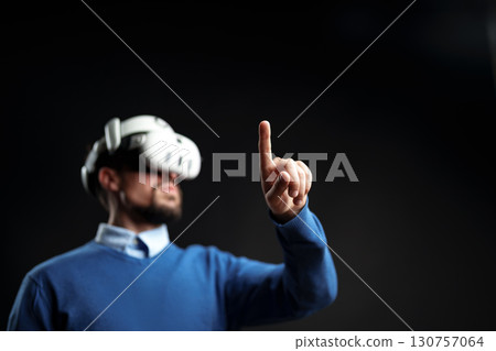 User engages in virtual reality experience while wearing VR headset indoors during a tech demonstration User engages in virtual reality experience while wearing VR headset indoors during a tech demonstration 130757064