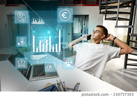 Young man analyzing financial data while talking on the phone in a modern office setting 130757303