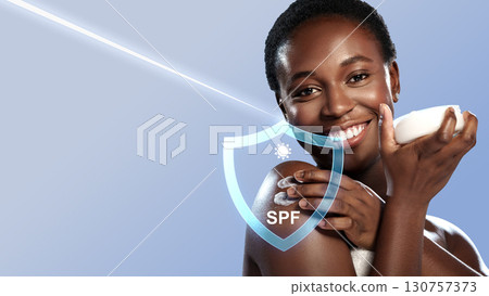 Woman applying moisturizer with a joyful smile against a light blue background during a skincare routine 130757373