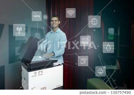 Young man using a multifunction printer to scan documents while discussing digital connectivity features in a modern workspace 130757490