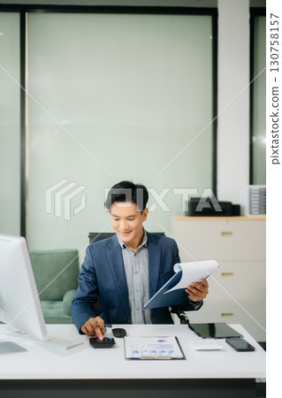 Asian businessman working with working notepad, tablet and laptop documents talking on the smartphone, tablet and laptop 130758157