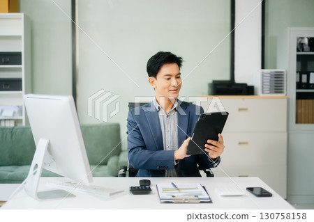 Asian businessman working with working notepad, tablet and laptop documents talking on the smartphone, tablet and laptop Asian businessman working with working notepad, tablet and laptop documents talking on the smartphone, tablet and laptop 130758158
