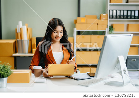 Woman Entrepreneur: SME Business mastering e-commerce with tablet, laptop, packaging, Woman Entrepreneur: SME Business mastering e-commerce with tablet, laptop, packaging, 130758213