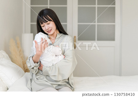 Bedroom, mother holding baby in bedroom (soothing, putting to sleep, childcare) 130758410