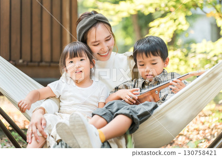 Family/family playing in a hammock at a campsite (outdoor/travel/leisure/picnic) Family/family playing in a hammock at a campsite (outdoor/travel/leisure/picnic) 130758421