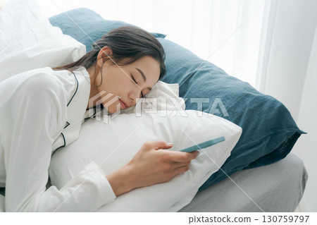 女人在床上操作智能手機 女人在床上操作智能手機 130759797