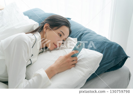 Woman operating smartphone in bed 130759798