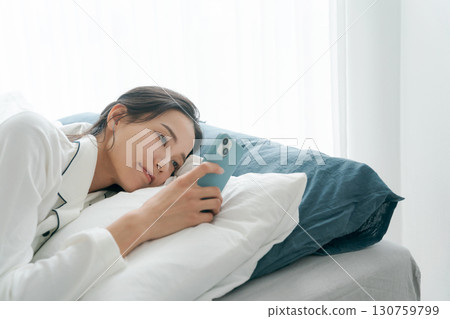 Woman operating smartphone in bed Woman operating smartphone in bed 130759799