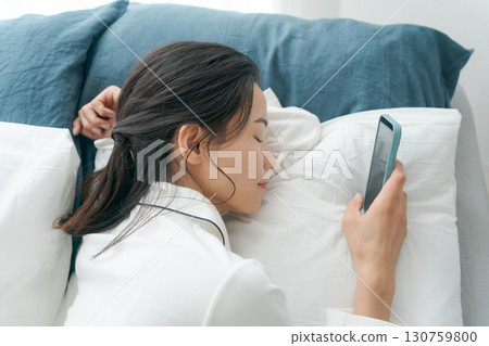 女人在床上操作智能手機 女人在床上操作智能手機 130759800