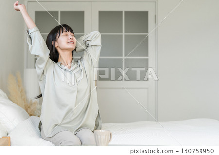 一位年輕的亞洲女性醒來後伸懶腰(睡眠良好、醒來、精神煥發) 一位年輕的亞洲女性醒來後伸懶腰(睡眠良好、醒來、精神煥發) 130759950
