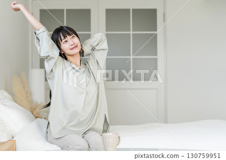 一位年輕的亞洲女性醒來後伸懶腰(睡眠良好、醒來、精神煥發) 一位年輕的亞洲女性醒來後伸懶腰(睡眠良好、醒來、精神煥發) 130759951