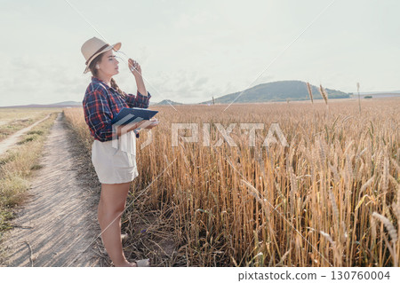 Young Woman Inspecting Wheat Field in Summer 130760004