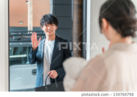 A young Asian woman/wife holding a baby seeing her husband off at the front door as he leaves for work in the morning A young Asian woman/wife holding a baby seeing her husband off at the front door as he leaves for work in the morning 130760798