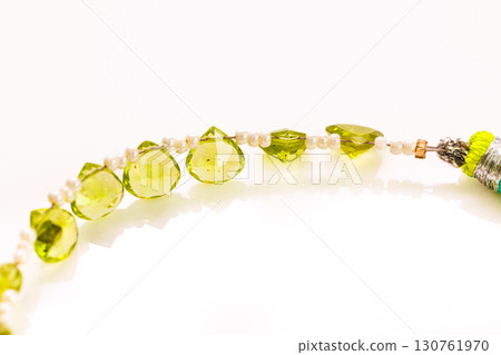 Peridot bead strands and tassels against a white background 130761970